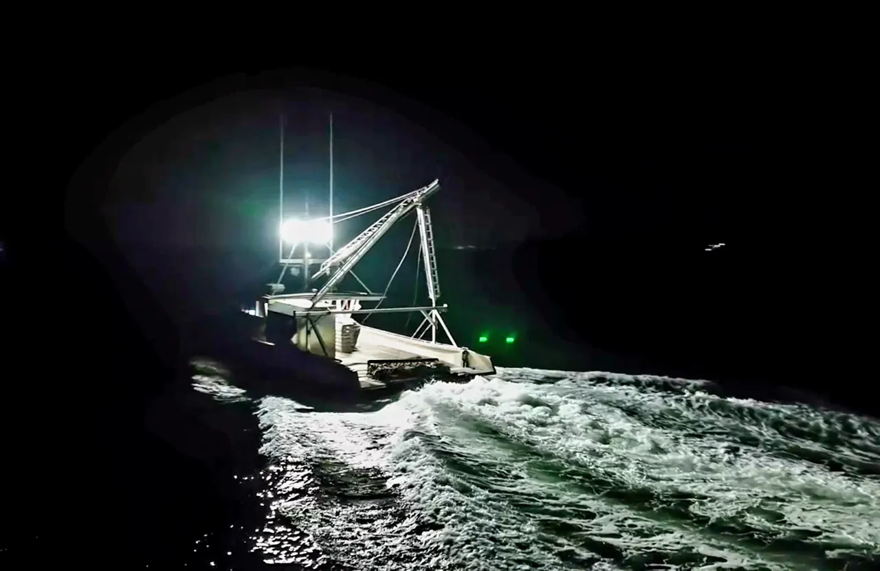 Aerial view at night of a workboat underway, its deck and wake lit by DuraBrite floodlights